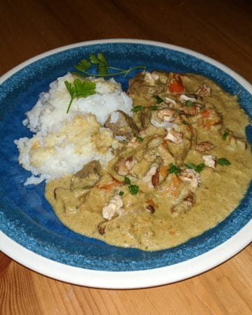 Beef korma with a parsley and walnut garnish, white rice on the side