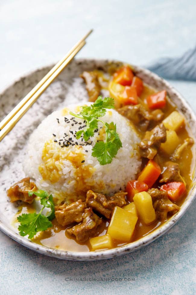 A golden Chinese curry with beef, potatoes, carrot and a scoop of rice
