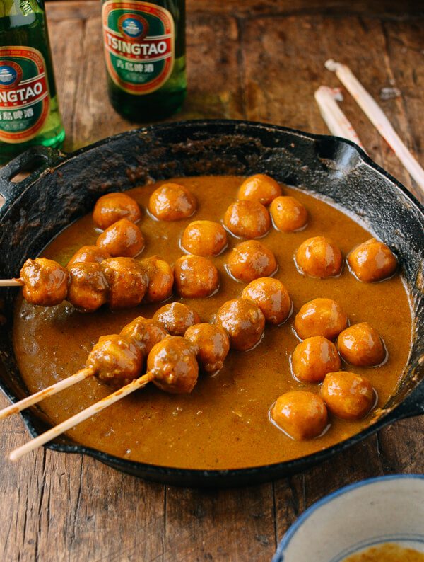 A soupy curry sauce with skewers of fish balls dipped into it