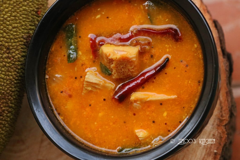 A soupy yellow curry with large red peppers and pieces of jackfruit