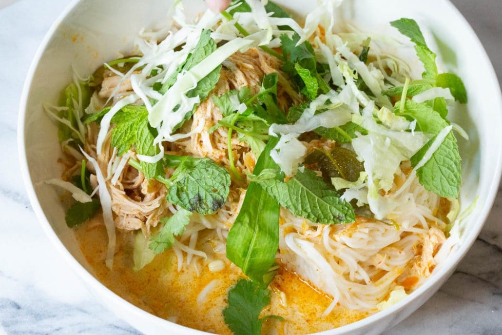 Noodles in a soupy yellow curry broth, topped with fresh basil and kaffir lime leaves