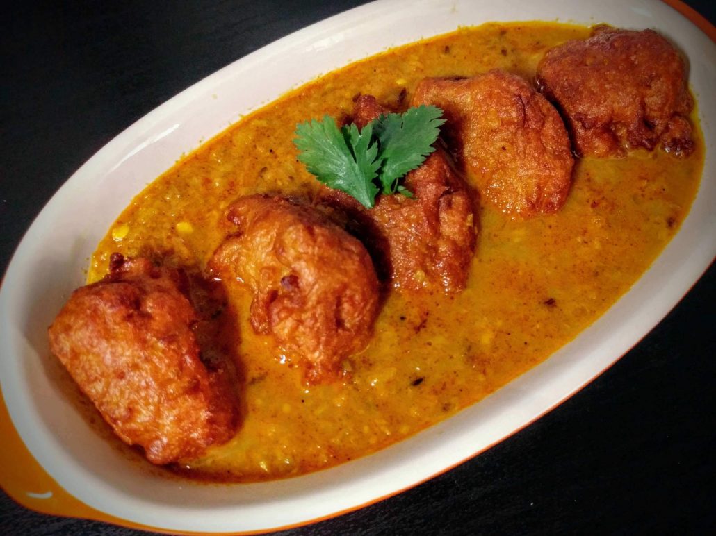 laukai koftas, or deep fried bottle gourd dumplings sitting in a tomato and onion curry