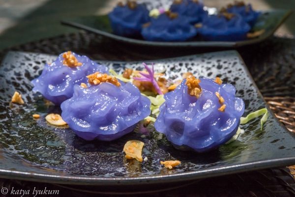 Blue Thai dumplings in the shape of a flower, with peanuts on top