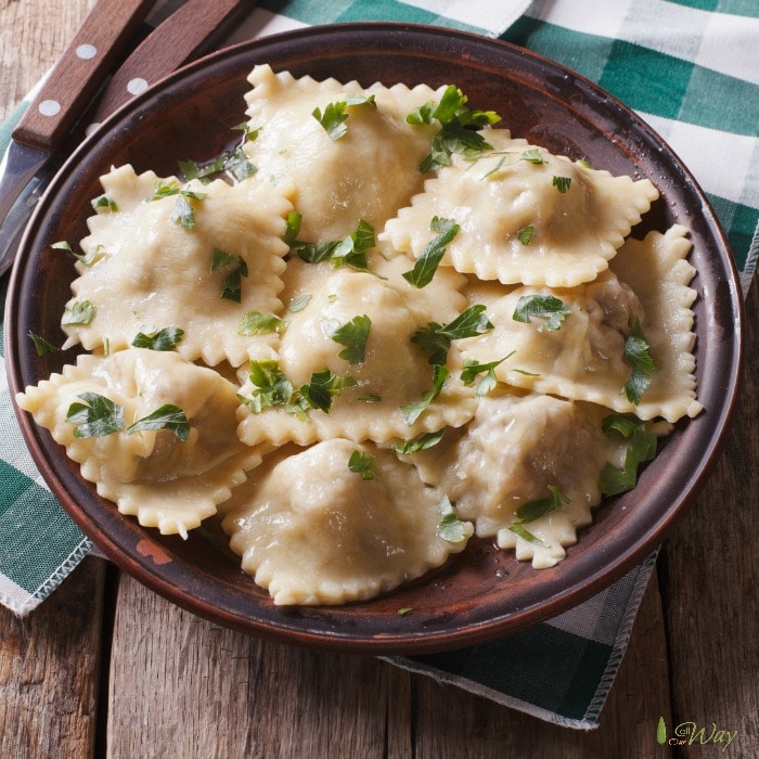 A bowl of ravioli, garnished with rosemary