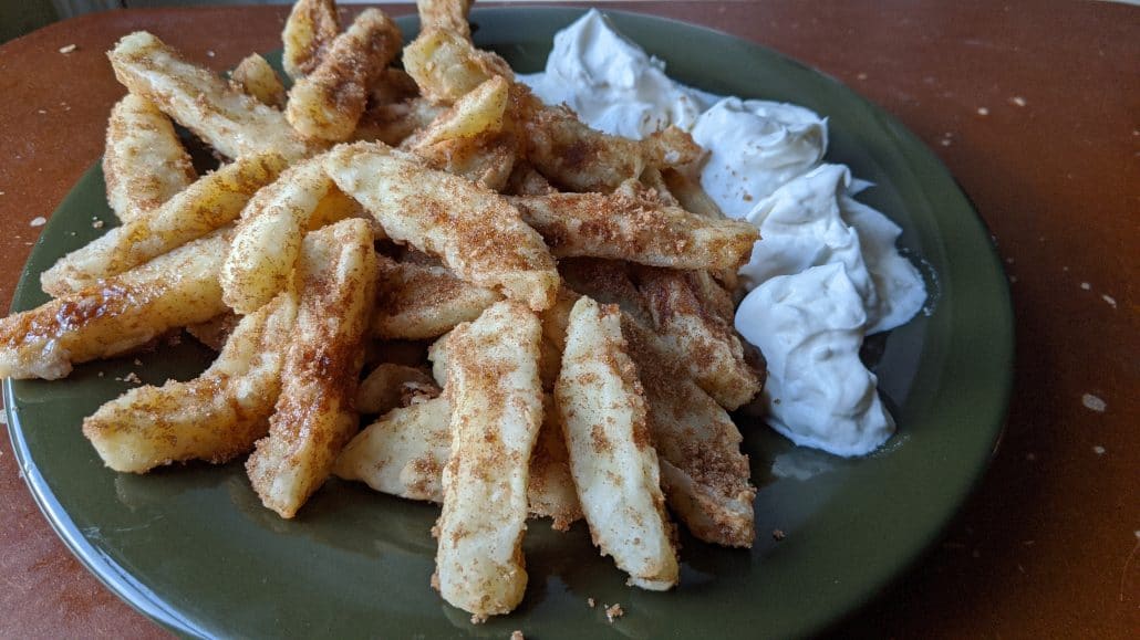 Apple fries covered in cinnamon sugar, with vanilla cream on the side