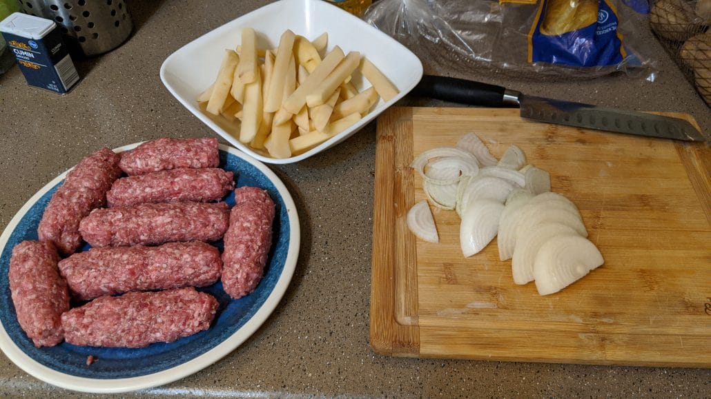 Raw kebapche, sliced onions, and sliced potatoes.