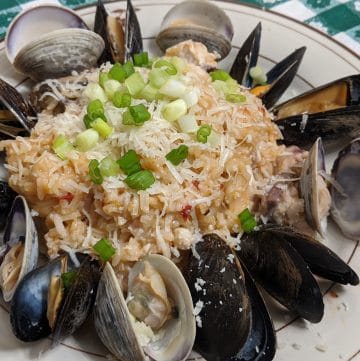 A plate of seafood risotto with red snapper, mussels, and clams
