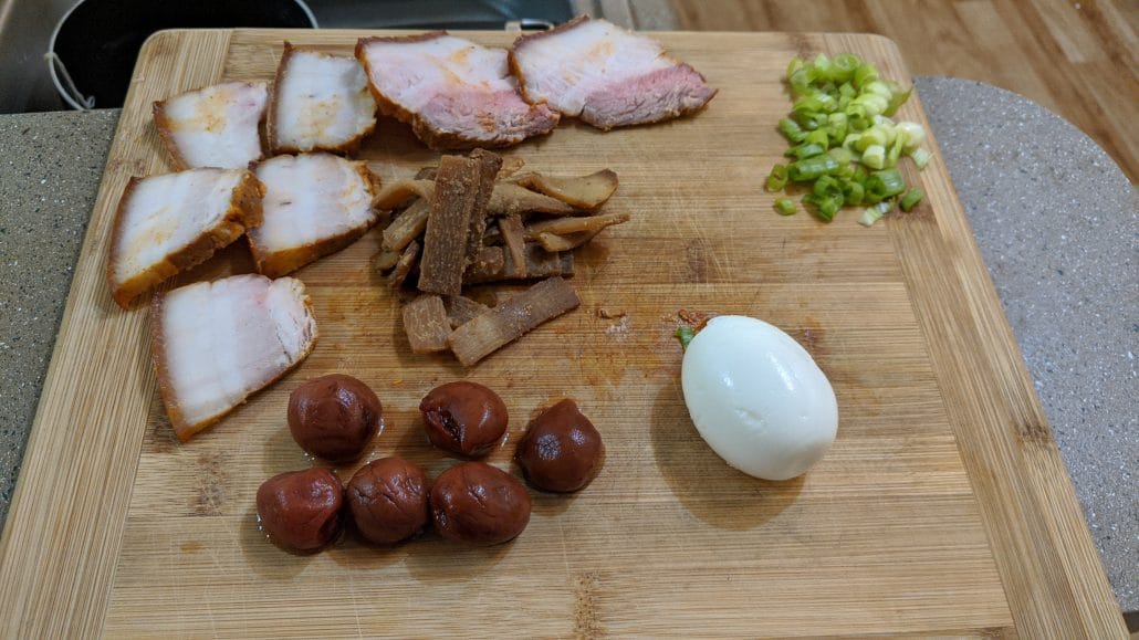 Asahikawa ramen toppings, including char siu pork, scallions, menma, softboiled egg, and umeboshi