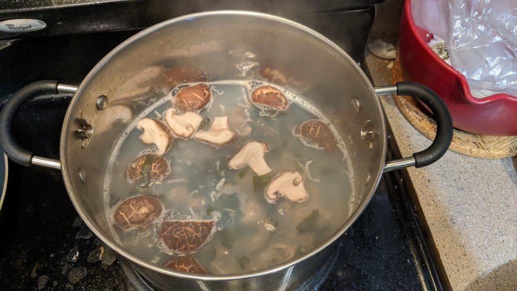 A boiling pot of mussels, shiitake mushrooms, wakame, and niboshi