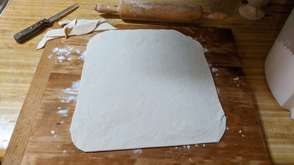 A sheet of ramen noodle dough on a cutting board