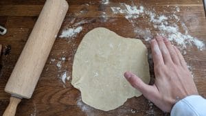 A rolled out tortilla, hand for scale