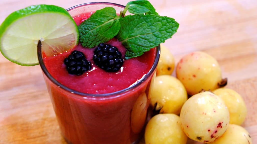 A glass of blackberry guava agua fresca with a spig of mint